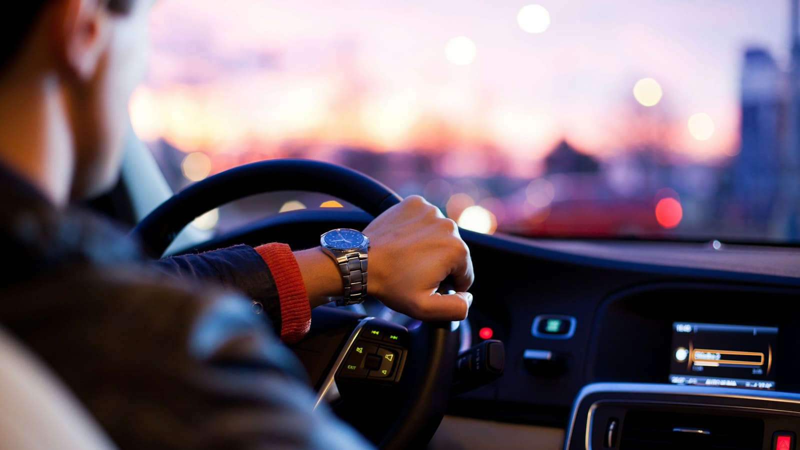 Mãos ao volante de um carro ao entardecer