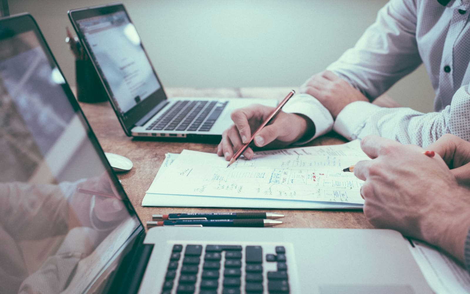 Pessoas analisando documentos em uma mesa de trabalho